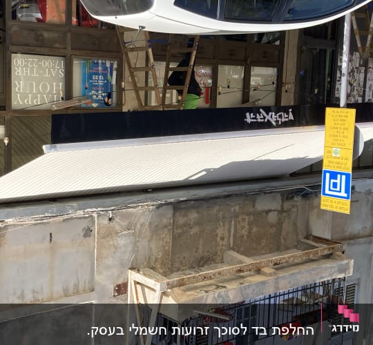 סוכך לבן מותקן מעל חנות עם שלט צהוב